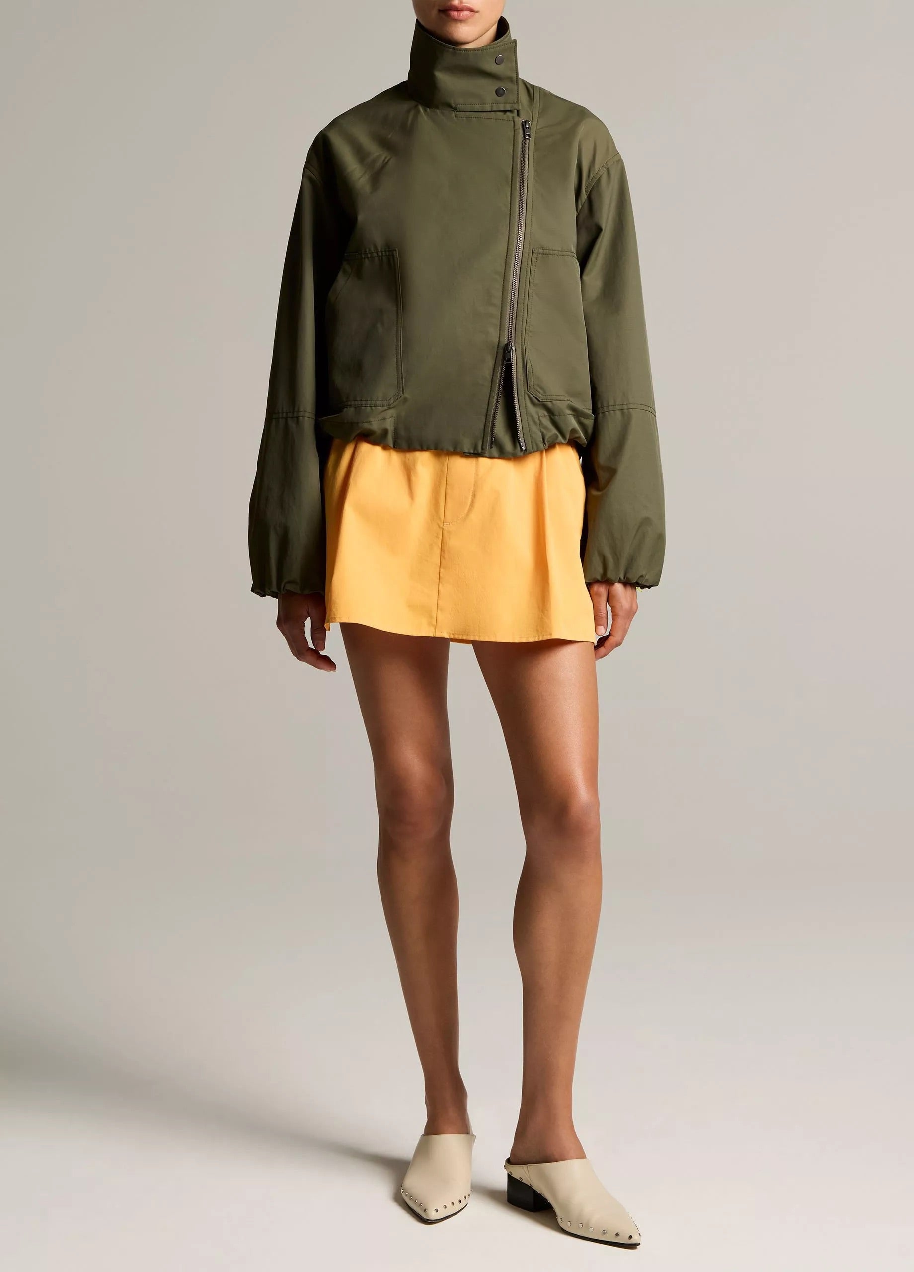 woman wears green jacket and yellow skirt
