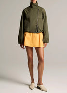 woman wears green jacket and yellow skirt