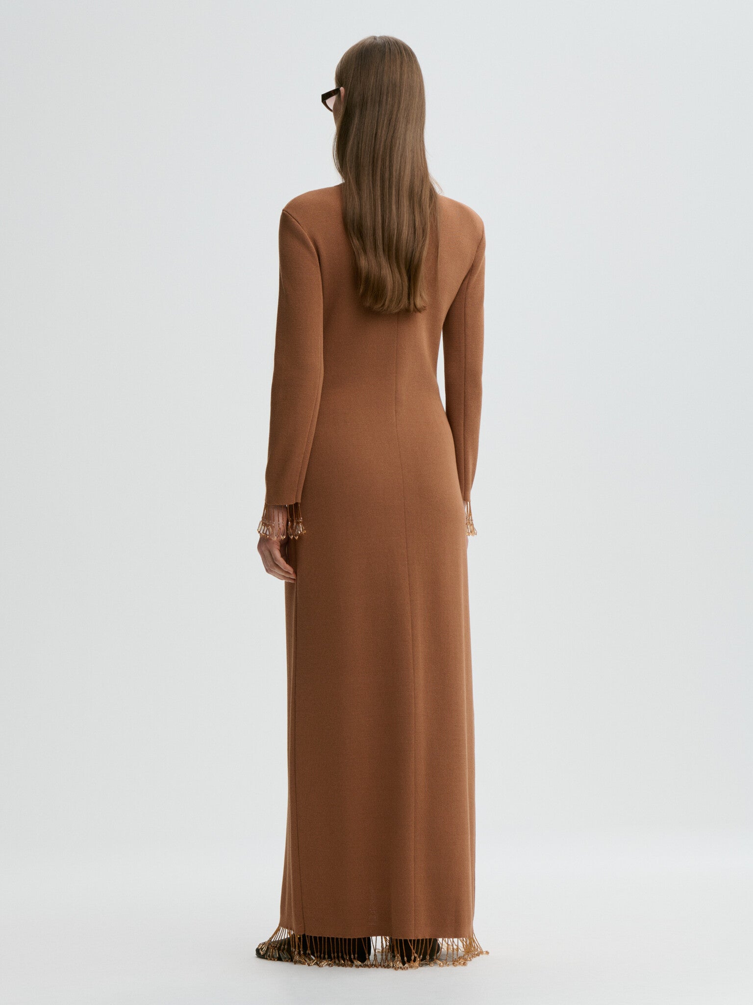 Woman wearing a long brown dress with a plain background