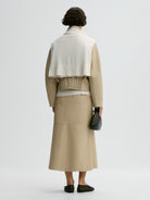 Person wearing a beige jacket and skirt set on a white background