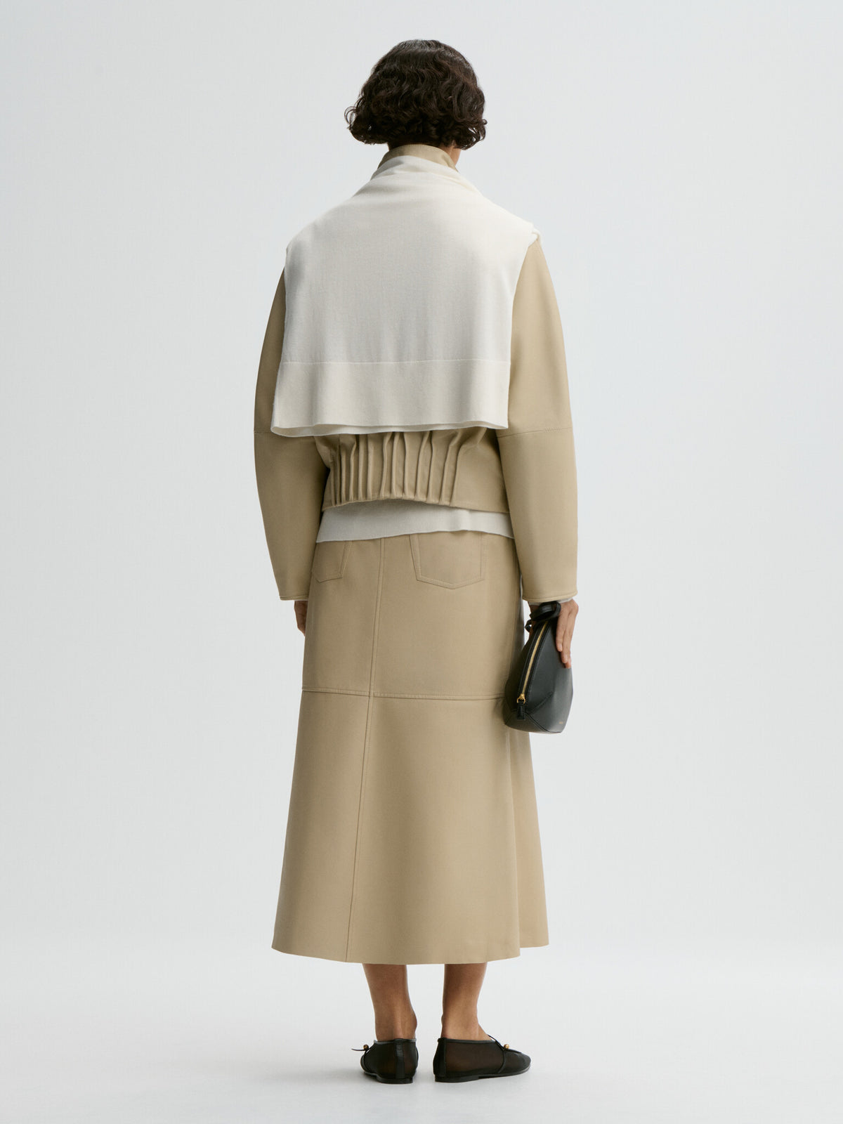 Person wearing a beige jacket and skirt set on a white background