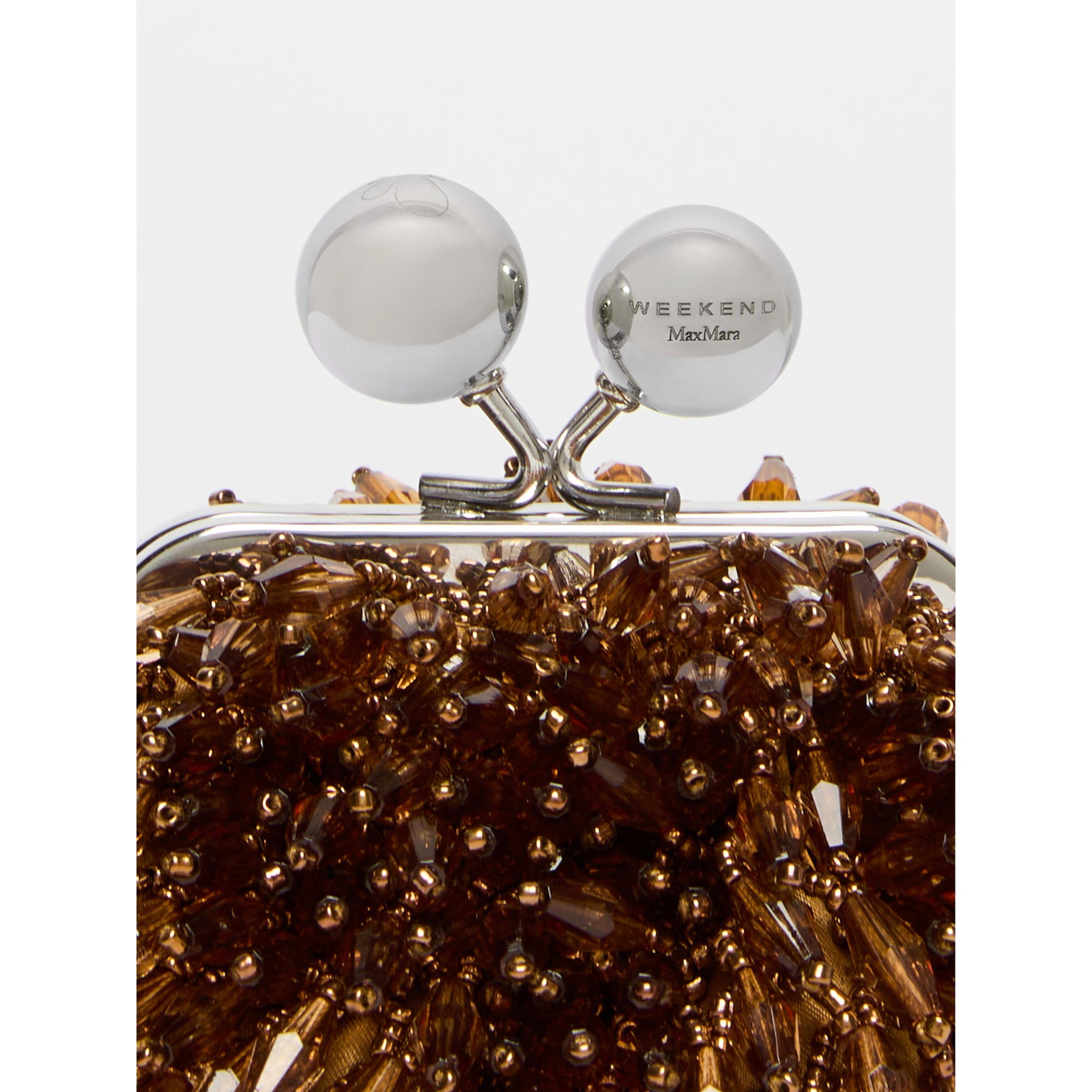 Close-up of a decorative clutch with gold beads and 'Weekend Maxmara' branding.