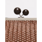 Close-up of a woven clutch bag with wooden clasp on a white background