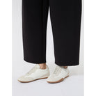 White sneakers worn with black pants on a white background