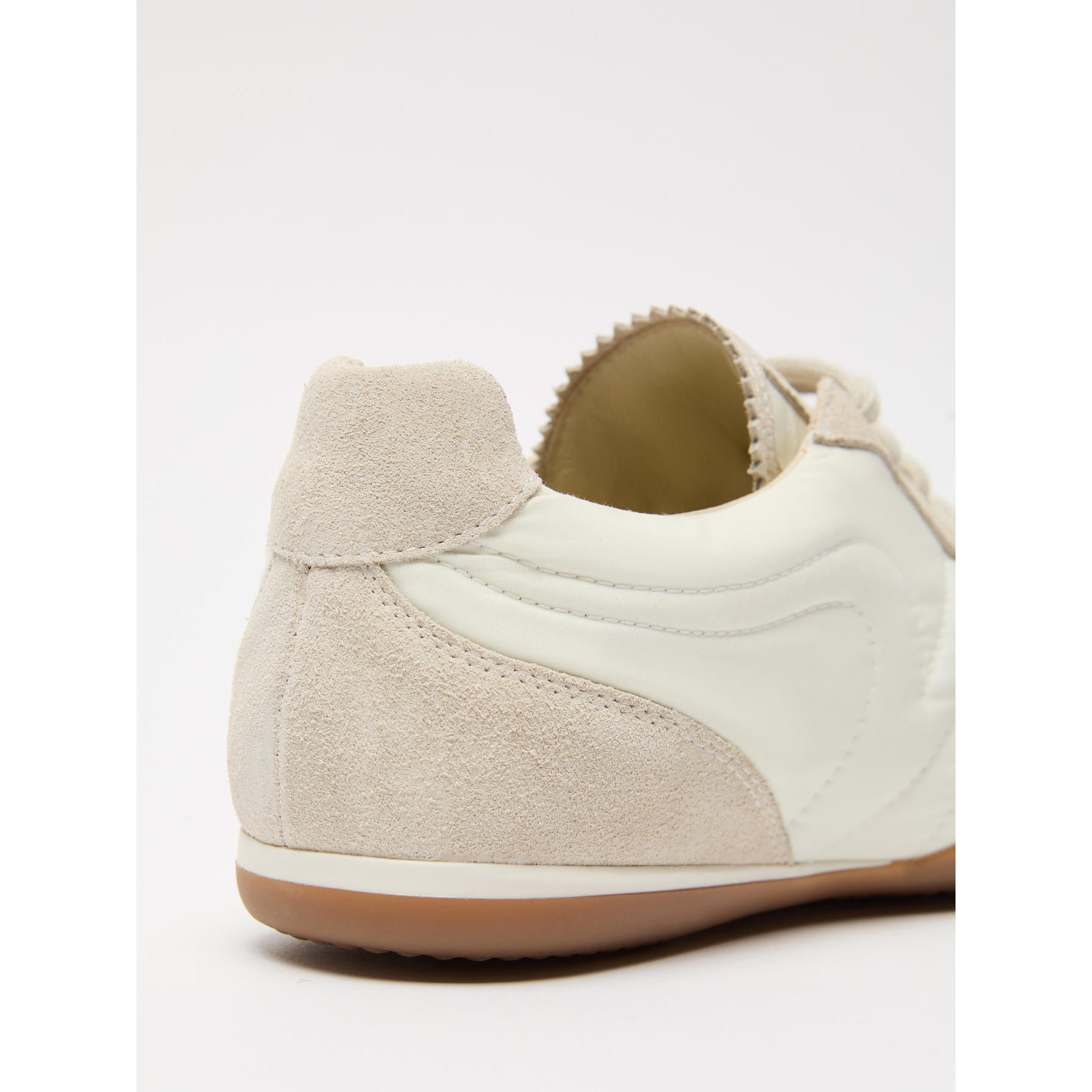 Close-up of a beige sneaker with a white sole on a light gray background