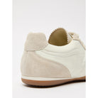 Close-up of a beige sneaker with a white sole on a light gray background
