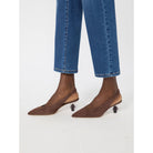 Brown pointed-toe shoes worn with blue jeans on a white background