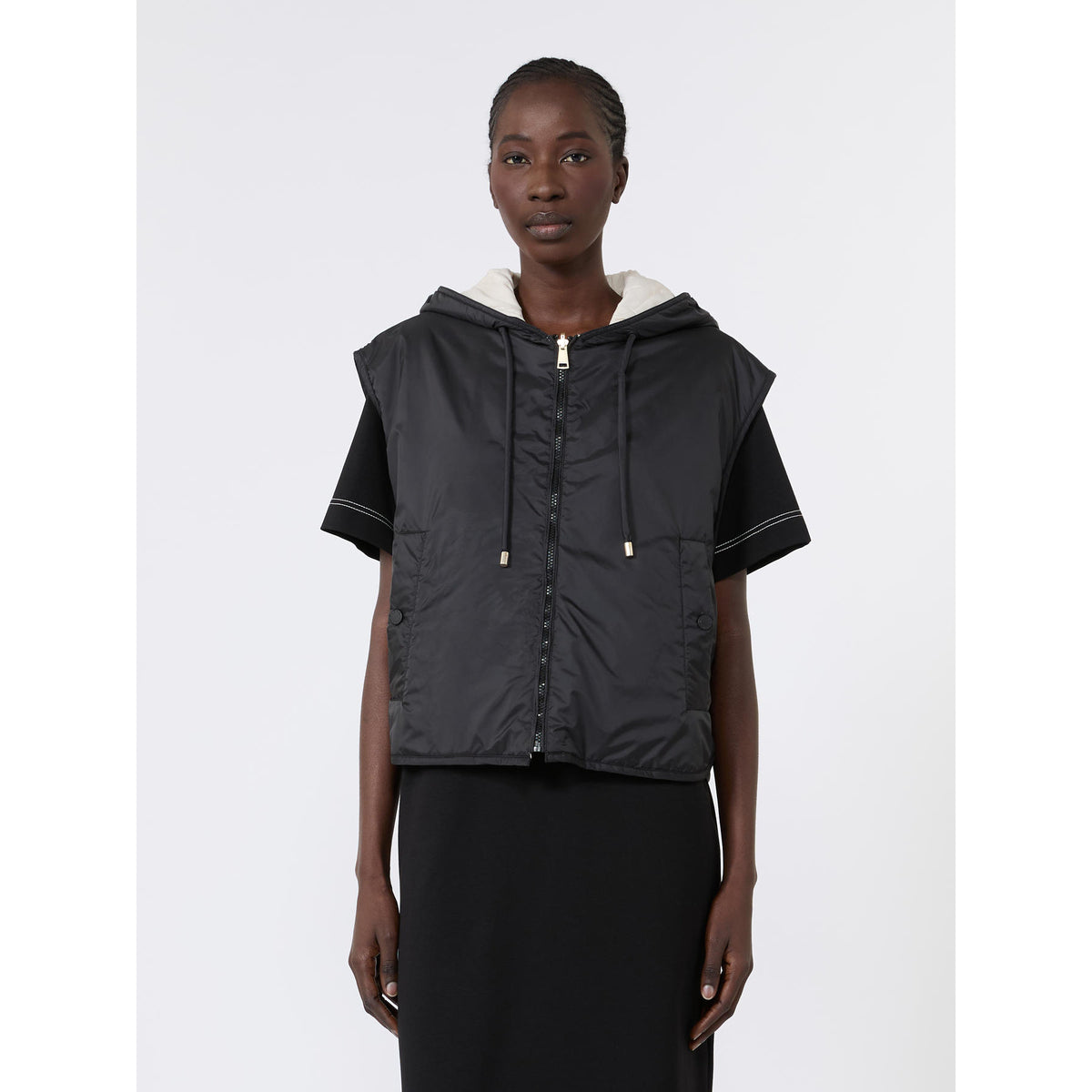 Person wearing a black hooded vest on a white background