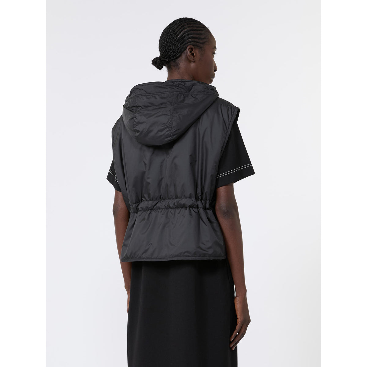 Person wearing a black hooded vest on a white background
