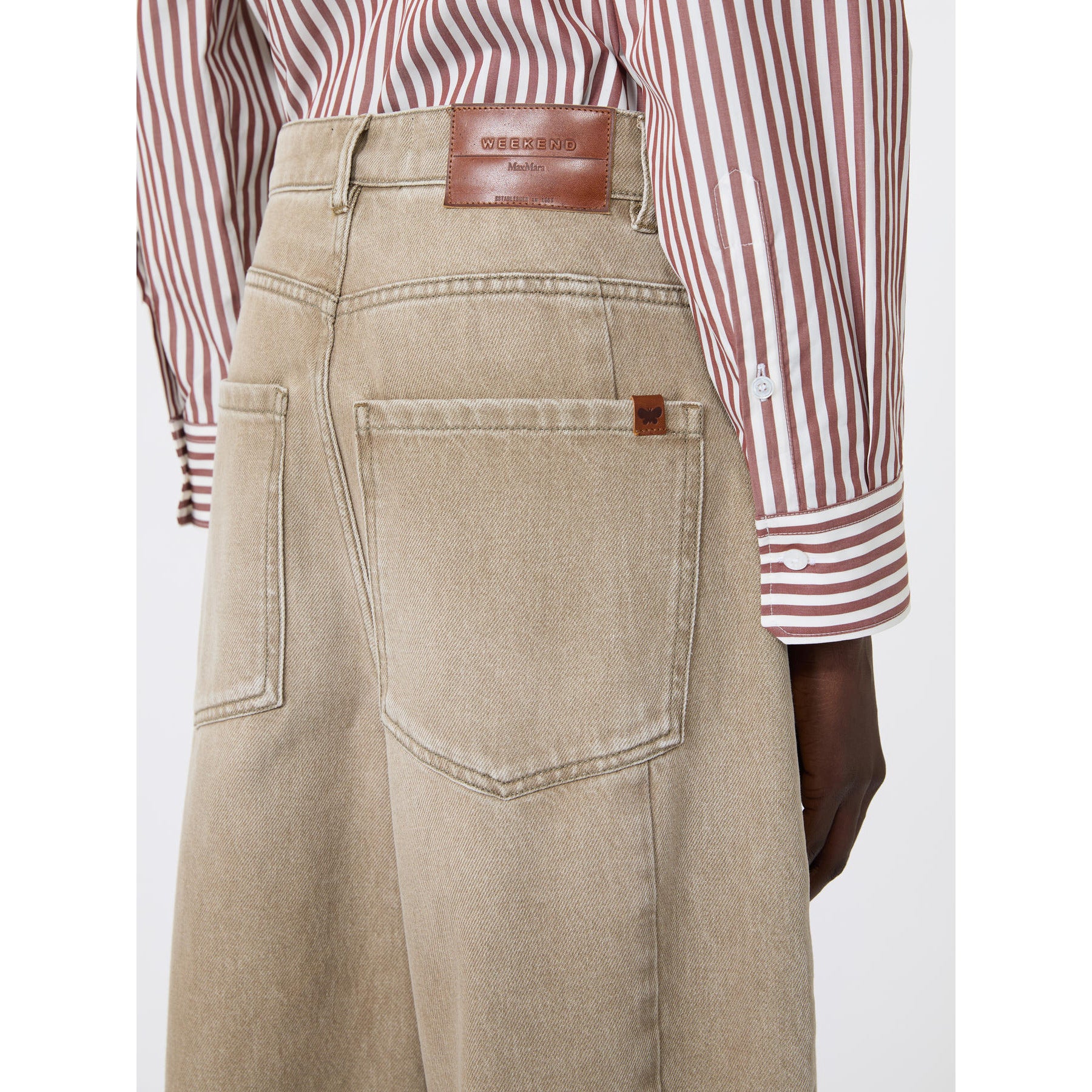 Beige pants with a brown leather belt and red and white striped shirt on a white background