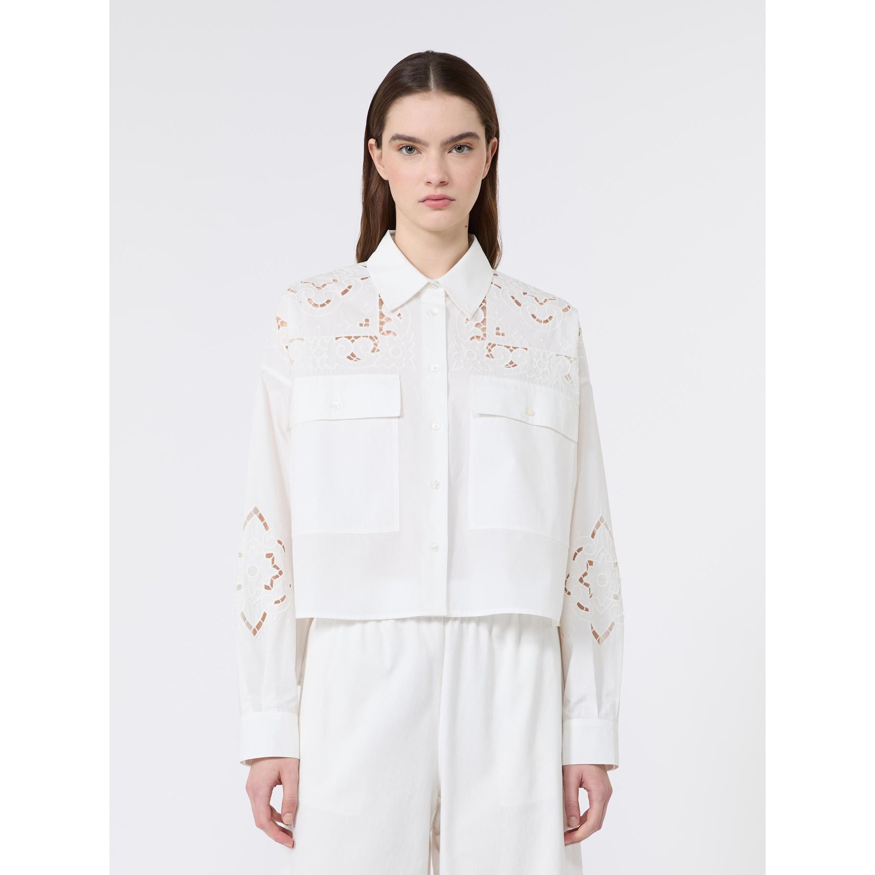 Woman wearing a white blouse with floral embroidery on a white background