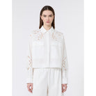 Woman wearing a white blouse with floral embroidery on a white background
