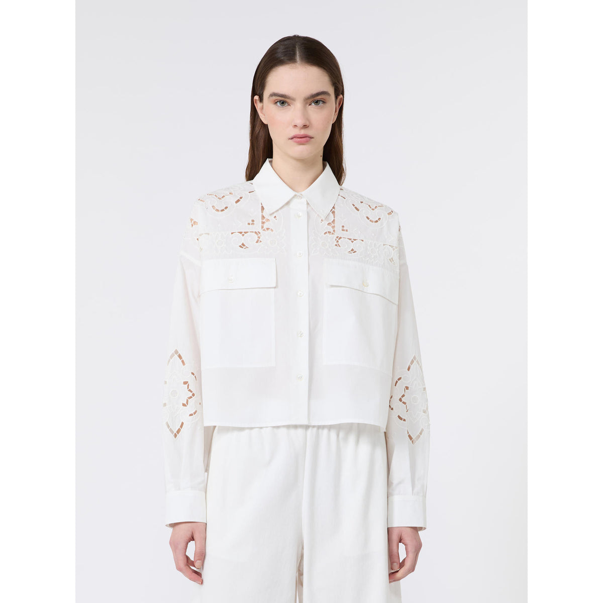 Woman wearing a white blouse with floral embroidery on a white background