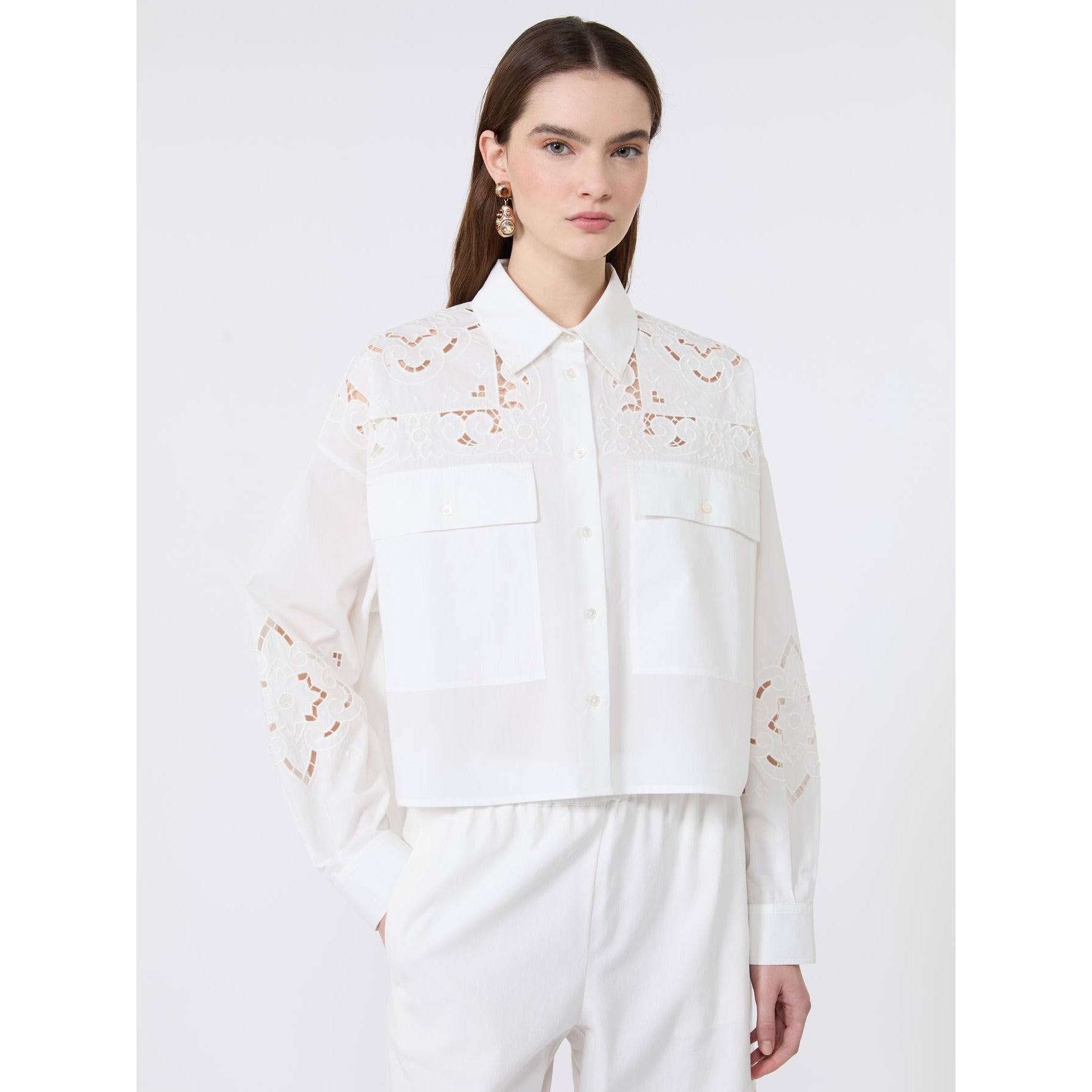 Woman wearing a white blouse with lace details on a white background