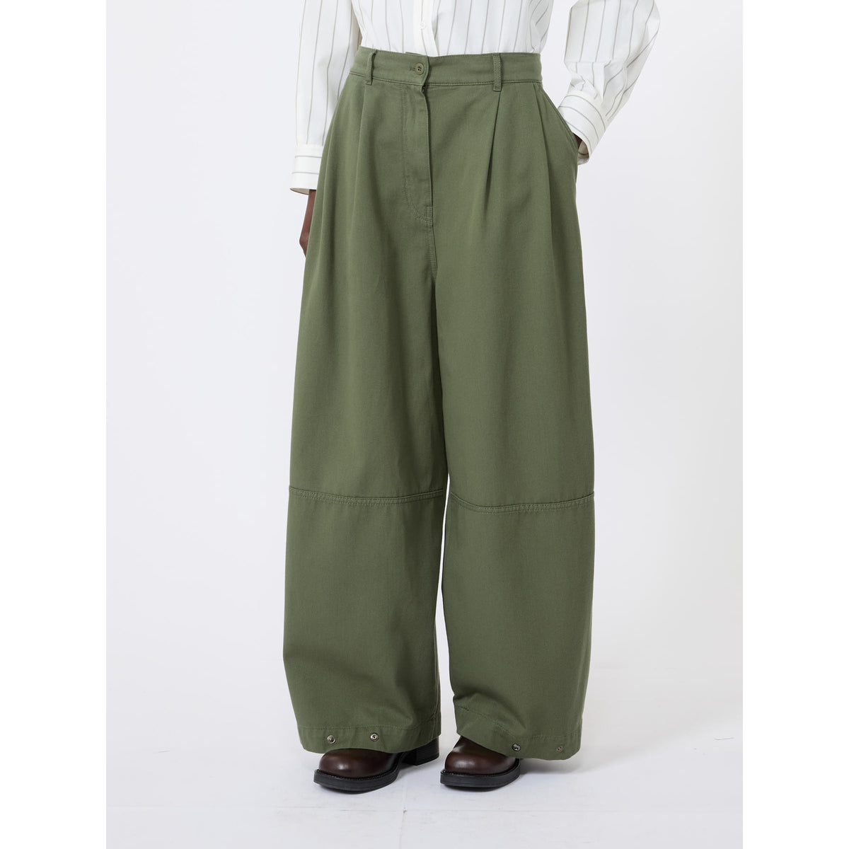 Green wide-leg pants worn with a white shirt on a white background