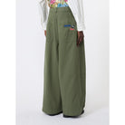 Person wearing green wide-leg pants with a brand logo on a white background