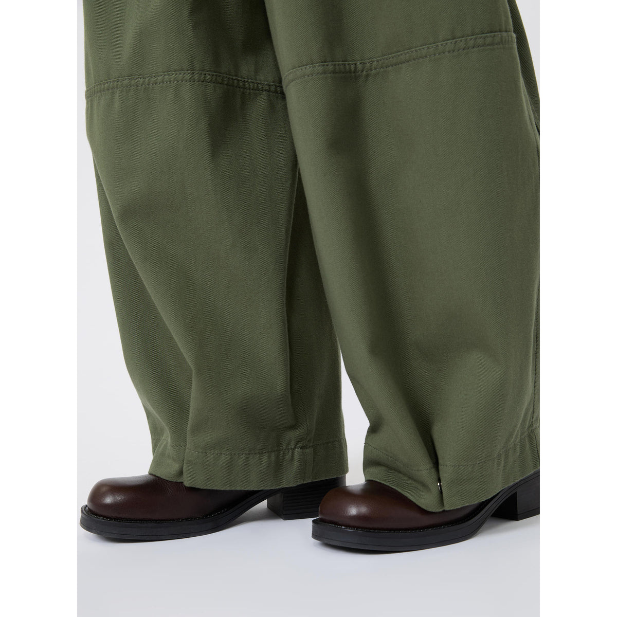 Green pants worn by a person on a white background