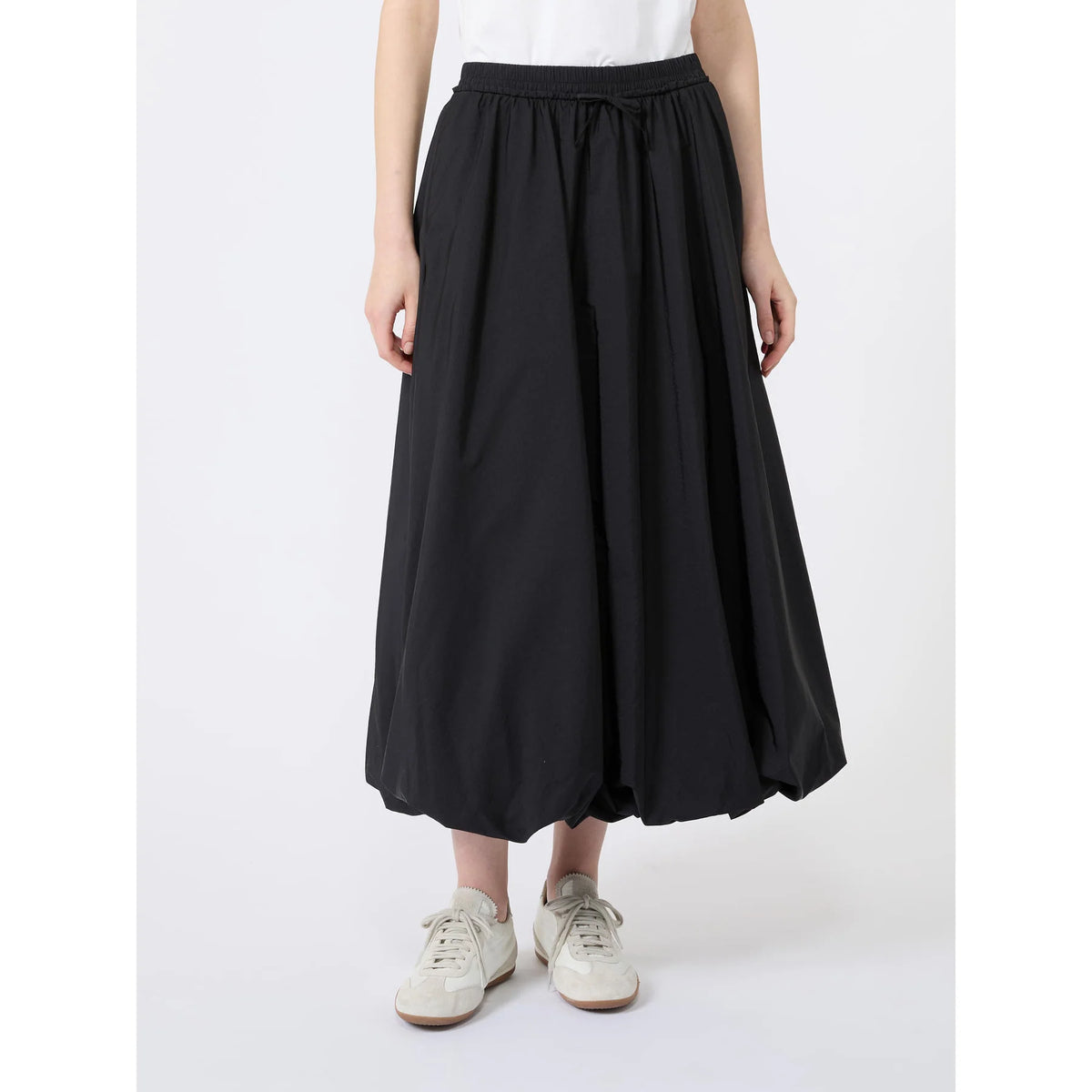 Person wearing a black wide-leg pants with a white top on a white background