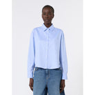 Person wearing a light blue shirt and jeans on a white background
