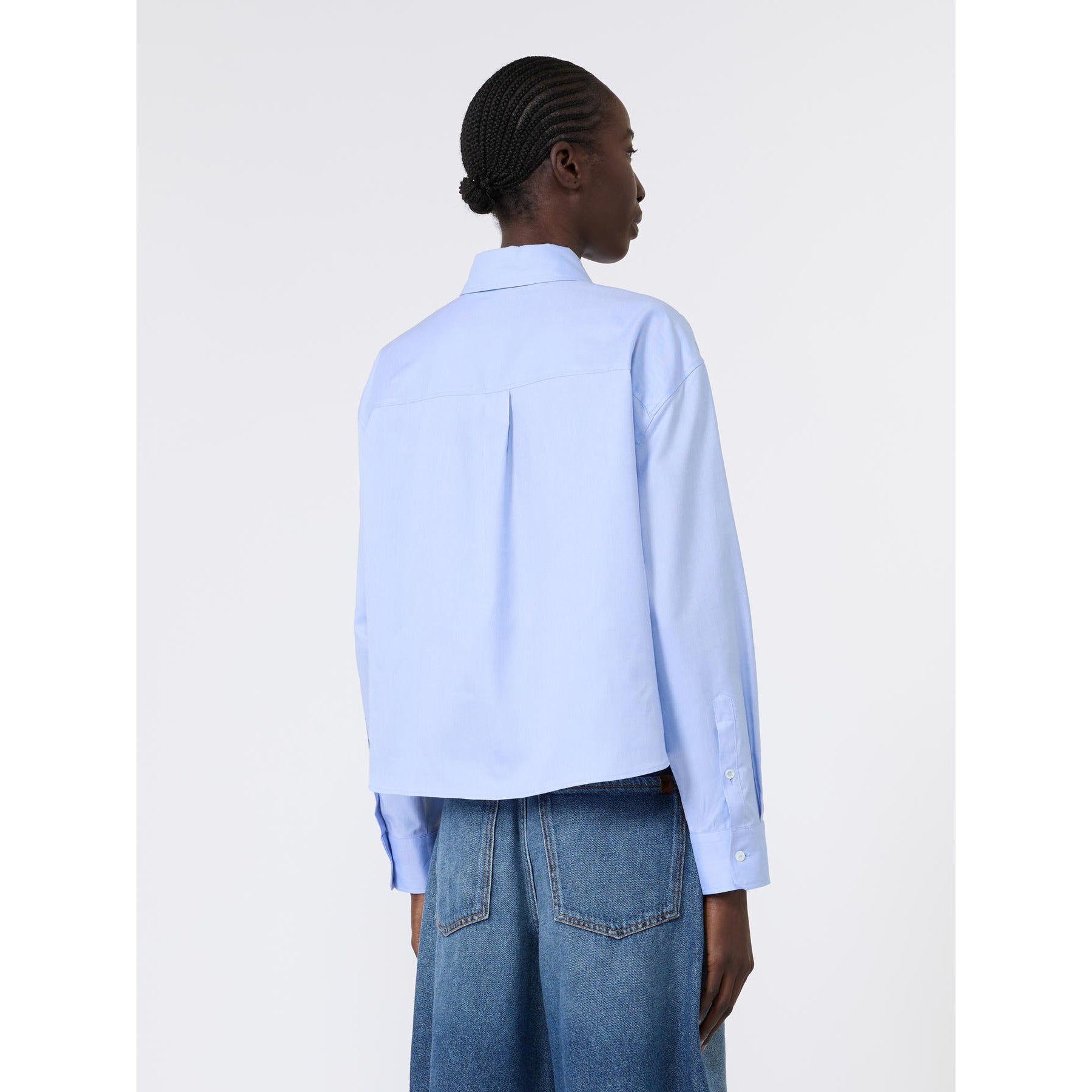 Person wearing a light blue shirt and blue jeans on a white background