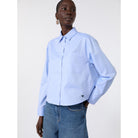 Person wearing a light blue shirt and jeans on a white background
