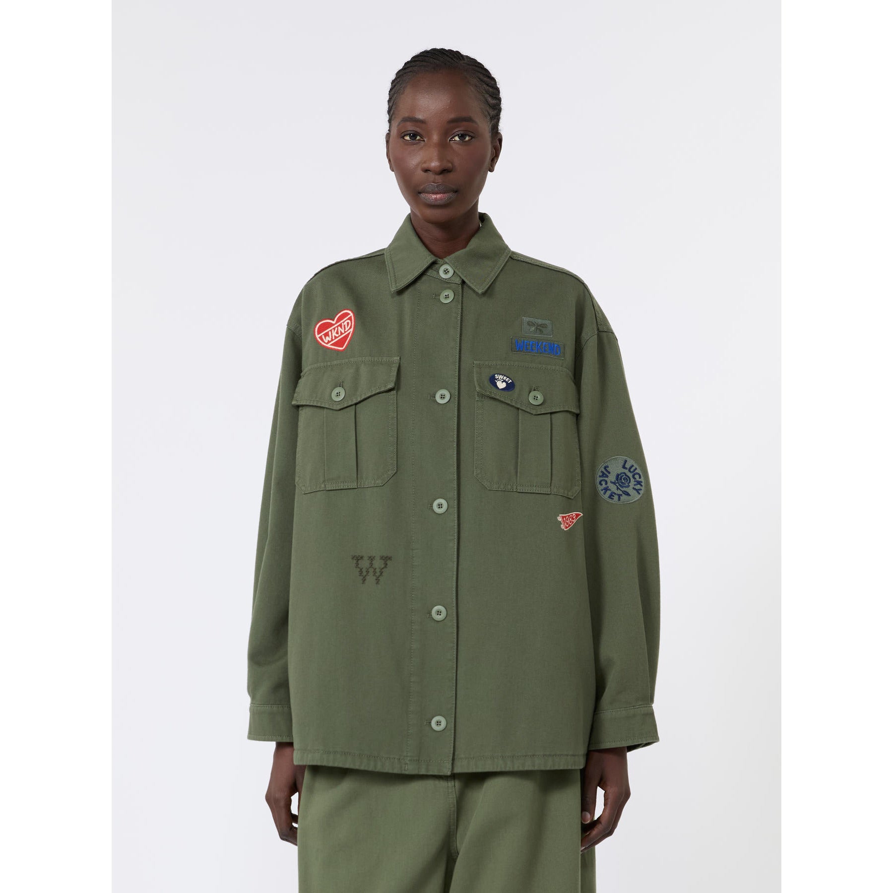 Person wearing a green jacket with patches on a white background