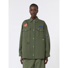 Person wearing a green jacket with patches on a white background