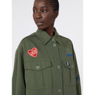 Person wearing a green jacket with patches on a white background