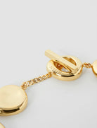 Close-up of a gold bracelet with a clasp on a light gray background