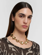 Woman wearing a gold necklace against a plain background
