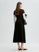 Woman wearing a dark top and black skirt with a white background