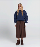 Person wearing a navy sweater and brown skirt on a white background