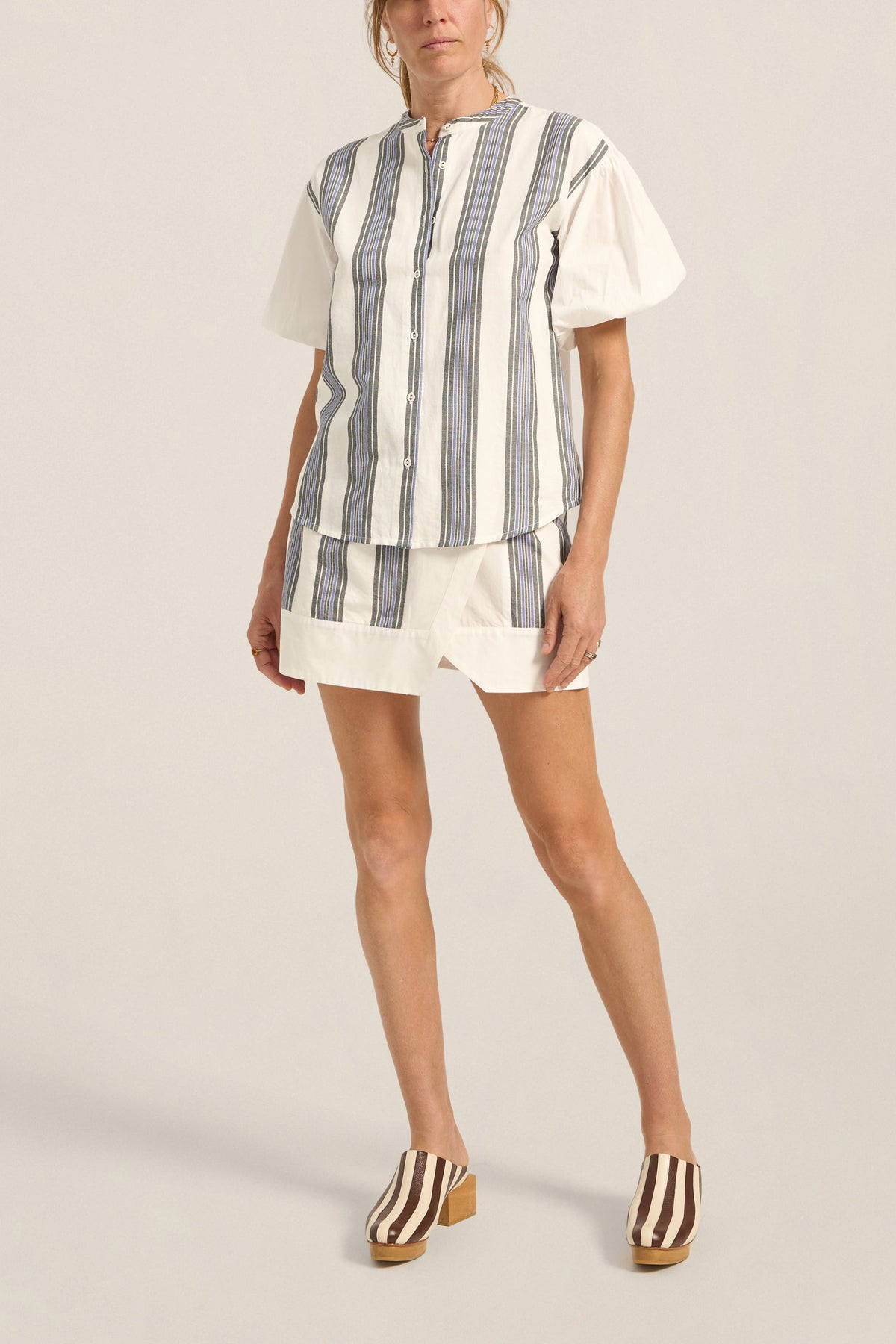 Woman wearing a striped shirt and shorts on a plain background