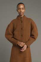 Person wearing a brown knitted dress against a gray background