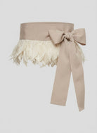 Beige belt with feathered top and bow on a light gray background